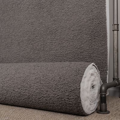 Ljusgrått möbeltyg med fårpäls känsla på rulle som visar struktur och tjocklek