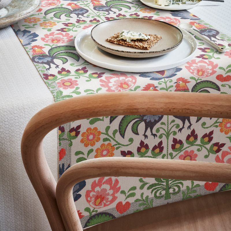 Svenskdesignad bordslöpare med charmiga blom- och bladmotiv i mjuka färger på en hållbar ekologisk väv, GOTS-märkt.
