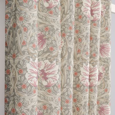 Närbild av gardintyg med blommor och blad i dimmgrönt och rosa toner