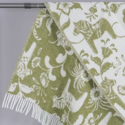 Närbild av ullpläd med dalahästar och blomdetaljer i gröna toner