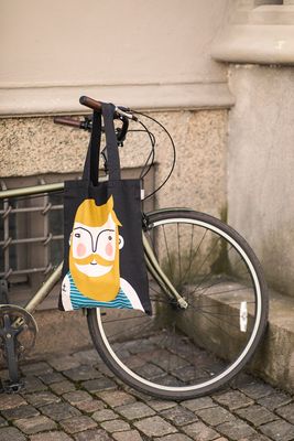 Svart tygkasse med motiv av Frank hängandes på en cykel utomhus