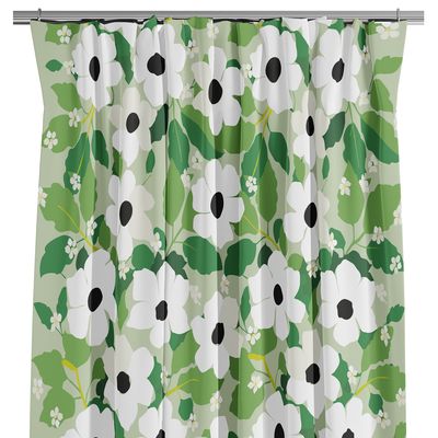 Gröna gardiner med vitt blommönster och svarta detaljer, upphängda på gardinstång